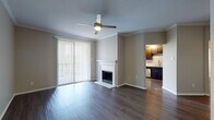 This single-story unit is finished with wood-style flooring that runs consistently throughout all rooms, lending a cohesive and clean aesthetic to the space. The living area serves as the focal point of the unit, featuring crown molding, a ceiling fan with integrated lighting, and a white-mantled fireplace. Large sliding glass doors fitted with vertical blinds allow natural light to flood the room while providing outdoor access. The living area flows directly into the kitchen, which is outfitted with dark espresso cabinetry, light countertops, a subway tile backsplash, and a full suite of stainless steel appliances including a gas range, over-the-range microwave, and refrigerator.

The bedrooms are well-proportioned, each equipped with ceiling fans, ample natural light from large windows with outdoor views of greenery, and access to closets. Crown molding is present in select rooms, adding a refined architectural detail.

The bathroom features dark cabinetry paired with light countertops, a dual-sink vanity, a large mirror, and a tub and shower combination with a curved rod. Wood-style tile flooring ties the bathroom finish seamlessly to the rest of the unit's design.