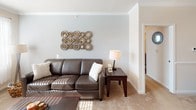 This single-floor residence offers a thoughtfully arranged layout that balances comfort and functionality across its key living spaces. The living room is finished with soft carpet, crown molding, and light-toned walls that reflect natural sunlight streaming in through the windows, creating a warm and inviting atmosphere. The space connects seamlessly to a dedicated dining area, which features a chandelier overhead and chair-rail molding along the walls, adding a classic architectural detail.

The kitchen is designed in a galley configuration, equipped with warm oak cabinetry, laminate countertops, and tile-style flooring. It includes a full suite of appliances and opens toward an entryway, providing convenient access throughout the unit.

Both bedrooms are carpeted and generously proportioned, each featuring a ceiling fan, ample natural light from windows, and open closet space. The primary bedroom benefits from an en-suite bathroom, while a second full bathroom serves the remainder of the residence. Both bathrooms include vanities with wood cabinetry, large mirrors, and tub-shower combinations with wood-look flooring.

An additional utility room with wire shelving and tile-style flooring offers practical storage and utility connections, completing this well-organized residence.