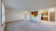 Located at 3795 S Rivershire Dr in Greenfield, Wisconsin, this single-floor unit offers a practical and functional layout designed for comfortable everyday living. The open-concept living and dining area is generously sized, featuring neutral-toned carpeting, warm wood baseboard trim, and crisp white walls that create a clean, bright atmosphere. A pass-through peninsula connects the living space to the kitchen, enhancing the sense of openness and flow between rooms.

The kitchen is well-appointed with warm oak cabinetry offering ample upper and lower storage, white countertops, and a full suite of black appliances including a refrigerator, electric range, and over-the-range microwave. Light tile flooring completes the kitchen's practical design.

The bedrooms are carpeted and feature wood-trimmed windows fitted with blinds that allow for natural light while maintaining privacy. Baseboard heating units are present throughout, ensuring consistent warmth. One room includes a wall-mounted AC unit for added climate control. A dedicated room with tile flooring includes a closet with sliding doors, offering flexible use as a bedroom or utility space.

The bathroom features a full-size soaking tub and shower combination with clean white surround and chrome fixtures. Throughout the unit, consistent warm wood trim and neutral finishes contribute to a cohesive, move-in-ready environment.