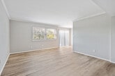 This single-floor, 2-bedroom, 1-bathroom home offers a well-organized layout designed for comfortable everyday living. The open living area greets you with light-toned hardwood-style flooring, neutral-painted walls, and crown molding that adds a refined touch to the space. Windows along the exterior wall invite natural light and provide views of the surrounding greenery, enhancing the bright and airy feel of the room. A connecting hallway leads to the remaining rooms, providing a clear and logical flow throughout the home.

The kitchen is efficiently designed, featuring light wood cabinetry with modern hardware, granite-style countertops, and a full suite of appliances including an electric range, dishwasher, and refrigerator. Crown molding continues into the kitchen, tying together the overall aesthetic, while a flush-mount ceiling fixture provides ample overhead lighting.

Both bedrooms are carpeted for warmth and comfort. The generously sized primary bedroom includes a dedicated closet with a hanging rod, offering practical storage. The second bedroom also features a closet and benefits from natural light through a horizontal window. The full bathroom is clean and functional, complete with a tub-shower combination featuring built-in shelving. A hallway connects all rooms, completing this cohesive and well-appointed home.