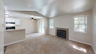 Located at 7720 Vineyards Ln NE in Bremerton, Washington, this single-floor residence offers a well-designed layout with a welcoming, neutral aesthetic throughout. The living area serves as the heart of the home, featuring plush carpeting, a tile-surround fireplace, and a ceiling fan. A sliding glass door and multiple windows invite natural light and provide access to an outdoor space, creating an airy, open atmosphere. The kitchen is efficiently laid out with white cabinetry, light countertops, wood-look flooring, and black appliances including a refrigerator and electric range. A pass-through counter connects the kitchen to the main living and entry areas, enhancing the sense of flow. The entryway corridor is finished with the same wood-look flooring, providing a clean transition from the front door into the living spaces. The bedroom is a quiet, carpeted retreat featuring a sliding double-door closet with built-in shelving and rod storage. The full bathroom is neatly appointed with a single-sink vanity, light countertop, a tub-shower combination, and wood-look flooring. Throughout the home, neutral wall tones and consistent finishes create a cohesive and practical living environment.
