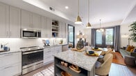 This thoughtfully designed single-floor residence offers a seamless blend of modern functionality and curated style. The heart of the home is a gourmet kitchen outfitted with floor-to-ceiling white shaker cabinetry, a white subway tile backsplash, stainless steel appliances including a range, microwave, dishwasher, and French door refrigerator, and warm wood-tone flooring. A large central island with striking granite countertops and contrasting dark cabinetry provides generous prep space and casual seating, illuminated by a pair of brushed gold pendant lights. The kitchen flows naturally into an open living area, where large windows invite natural light and offer views of the surrounding exterior. The living space is warm and inviting, styled with eclectic yet cohesive furnishings that lend the space personality and comfort. The bedroom is a calm retreat, featuring plush carpeting, a generous window with exterior views, and ample room for a full furniture arrangement. The full bathroom is elegantly detailed with dark cabinetry, granite countertops, a deep soaking tub with white tile surround, and rich gold-toned drapery accents. Throughout the residence, consistent use of granite surfaces, high-quality fixtures, and refined finishes creates a cohesive and polished aesthetic.