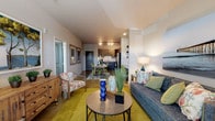 Located at 600 67th Ave N in Myrtle Beach, South Carolina, this single-floor unit offers a thoughtfully designed open-concept layout that seamlessly connects the kitchen, dining, and living areas. The living room provides a comfortable, well-lit space with multiple windows allowing natural light to fill the room, complemented by neutral walls and a coastal-inspired aesthetic throughout.

The kitchen is outfitted with dark shaker-style cabinetry, granite countertops, stainless steel appliances including a refrigerator, electric range, and over-the-range microwave. A built-in wine rack adds a distinctive touch. Adjacent to the kitchen, a dedicated nook features a granite-topped desk with dark cabinetry below and open wood shelving above, ideal for a home office setup.

The dining area accommodates a full-sized table and connects naturally to the living space, enhancing the open flow. The bedroom is generously sized, featuring a ceiling fan, ample natural light, and access to a walk-in closet. The bathroom is finished with dark cabinetry, granite countertops, a large mirror with lighted vanity, upper storage cabinet, and a shower-tub combination. The space maintains a cohesive coastal-modern character throughout.