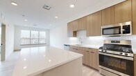 Located at 308 NJ-31 in Flemington, NJ, this thoughtfully designed one-bedroom, one-bathroom residence offers a clean, contemporary aesthetic across a efficiently laid-out single floor. Light hardwood flooring flows throughout the space, complementing the bright white walls and modern finishes.

The open-concept kitchen is a standout feature, showcasing warm wood cabinetry, white quartz countertops, a classic subway tile backsplash, and a full suite of stainless steel appliances including a gas range, dishwasher, microwave, and French door refrigerator. A central kitchen island provides additional prep and seating space, seamlessly connecting to the living area.

The living room benefits from a large window that fills the space with natural light and offers outdoor views. The bedroom is comfortably sized, featuring an expansive multi-pane window with open views, light hardwood floors, and clean white walls, creating a calm and airy retreat. A dedicated closet provides organized storage.

The bathroom is finished in a modern style with large-format floor tile, a wood-toned vanity with white countertop, a framed mirror, and chrome fixtures. A hallway connects the rooms efficiently, and an in-unit stacked washer and dryer adds everyday convenience. Recessed lighting throughout enhances the space's bright, polished atmosphere.