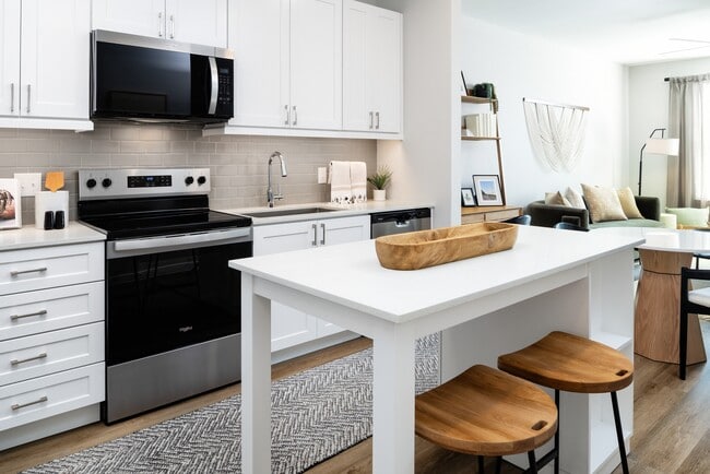 Paquete de acabados I Cocina con electrodomésticos de acero inoxidable, gabinetes blancos, placa para salpicaduras de azulejos grises, encimeras de cuarzo blanco y pisos de superficie dura. - Avalon Tech Ridge