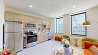 Located at 101 N Broadway Ave in the heart of downtown Oklahoma City, this one-bedroom, one-bathroom unit offers a thoughtfully designed single-floor layout that maximizes every square foot. A bright, clean hallway with recessed lighting and terrazzo-style flooring welcomes you inside, leading into the open-concept kitchen and living area. The kitchen is well-appointed with light wood shaker cabinets, white quartz countertops, a subtle tile backsplash, and a full suite of stainless steel appliances including a range, microwave, dishwasher, and refrigerator. Large windows allow natural light to fill the combined living space, creating an airy, inviting atmosphere. The bedroom is a calm, carpeted retreat featuring a ceiling fan, a built-in closet with double doors, and gold-toned hardware accents. The bathroom is stylishly finished with classic white hex tile flooring with black dot accents, marble-look surround tile in the tub/shower, light wood cabinetry, a dark countertop, and warm brass fixtures. A dedicated in-unit laundry area adds everyday convenience. Clean white walls and consistent gold hardware details throughout lend the space a cohesive, modern aesthetic.