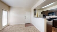 This 1-bedroom, 1-bathroom unit offers a practical and efficient single-floor layout designed for comfortable everyday living. The open-concept living area greets you at the front entry, featuring neutral-toned carpet, clean white walls, and a ceiling fan that enhances airflow and comfort. A pass-through counter connects the living space to the kitchen, creating a seamless flow between the two areas.

The kitchen is well-equipped and functional, showcasing rich dark espresso cabinetry, granite-style countertops, and stainless steel appliances including a range, microwave, and refrigerator. Wood-look flooring runs throughout the kitchen, adding warmth and visual contrast to the space.

The bedroom is a comfortable retreat, carpeted for coziness and fitted with a ceiling fan and a window with blinds that allows natural light to filter in. A private door provides additional access or closet space adjacent to the room.

The bathroom features a full tub and shower combination with white tile surround and chrome fixtures, complemented by tile flooring. A dedicated laundry area houses washer and dryer hookups alongside the water heater and electrical panel, providing all essential utilities in one convenient space. The unit's neutral palette and functional design make it a versatile and move-in-ready home.