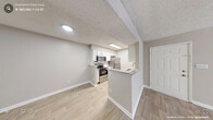 This single-floor home offers a thoughtfully designed layout across three bedrooms, two bathrooms, and key living spaces connected by a central hallway. Neutral warm-beige tones and light wood-look flooring flow throughout the main areas, creating a cohesive and clean aesthetic.

The living room is generously proportioned, featuring a ceiling fan, textured ceiling, and large windows that invite natural light. A glass-paned door provides additional brightness and outdoor access. The galley-style kitchen is well-equipped with white shaker cabinets, granite-style countertops, white subway tile backsplash, and stainless steel appliances including a refrigerator, range, microwave, and dishwasher. A peninsula counter opens toward the dining or entry area, enhancing the sense of flow.

The bedrooms feature plush carpet, ceiling fans, and ample wall space, with the primary bedroom offering direct access to one of the bathrooms. Both bathrooms are finished with granite-topped vanities and wood-look tile flooring; one includes a full tub-shower combination. Three closets distributed throughout provide practical storage. The overall design is clean, functional, and move-in ready.
