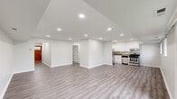 This single-floor, 2-bedroom, 1-bathroom unit offers a thoughtfully designed layout with clean, modern finishes throughout. The open-concept living room and kitchen area forms the heart of the home, featuring light gray luxury vinyl plank flooring, recessed lighting, and a sliding glass door that fills the space with natural light and provides outdoor views of greenery. The kitchen is well-equipped with white shaker-style cabinetry, granite-look countertops, a stainless steel refrigerator, gas range, and dishwasher — all positioned for a functional workflow. A warm-toned entry door anchors the front of the living space, adding a welcoming contrast to the bright, neutral palette. A hallway with recessed lighting connects the main living area to the private quarters, where both bedrooms feature plush carpeting, built-in closets with white bifold doors, and soft overhead lighting. The primary bedroom offers a comfortable footprint with dedicated closet storage. The bathroom includes a full soaking tub and shower combination with cream tile surround accented by a decorative mosaic tile border. A dedicated closet completes the layout, providing additional storage convenience.
