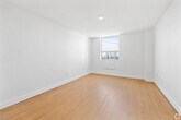 Located at 1577 Lawrence Avenue West in Toronto's Mount Dennis neighbourhood, this one-bedroom, one-bathroom unit offers a clean, modern interior across a single floor. The layout includes a living room, bedroom, kitchen, bathroom, and hallway, all finished in a bright, minimalist style with white walls and light wood laminate flooring throughout.

The living room is an open, well-lit space featuring large windows that bring in natural daylight and offer views of the surrounding greenery. The bedroom is a comfortable, well-proportioned room with its own window providing natural light and outdoor views, along with a built-in sliding double closet for convenient storage.

The kitchen is efficiently designed with white cabinetry, grey countertops, a stainless steel sink, and a tiled backsplash. It includes a freestanding electric range, making it fully functional for everyday cooking needs.

The bathroom is finished with clean white tilework, featuring a full-sized soaker tub with an overhead shower, and brushed nickel fixtures throughout. The hallway connects the rooms in a practical, space-conscious layout. Overall, the unit presents a tidy, move-in-ready space with a consistent, neutral aesthetic suited for comfortable urban living.