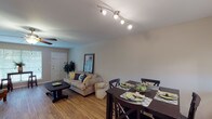 This single-floor, 2-bedroom, 1-bathroom residence is thoughtfully designed to maximize functionality and comfort. The entry foyer opens directly into a bright and welcoming living room, where wood-look flooring, a ceiling fan, and large windows work together to create an airy, well-lit atmosphere. The living area flows seamlessly into a dedicated dining space, anchored by a stylish track lighting fixture overhead and positioned adjacent to a pass-through window that connects to the kitchen.

The kitchen features granite-style countertops, white cabinetry, a coil-top range, and a stainless steel sink — offering an efficient and clean workspace. The pass-through window to the dining area enhances the open feel between spaces.

Both bedrooms are carpeted and equipped with ceiling fans. The primary bedroom includes a window that brings in natural light, while the second bedroom comfortably accommodates two twin beds and features matching wall décor for a cohesive look.

The full bathroom is finished with large-format tile surrounds in a warm earth tone, a soaking tub with shower combination, tile flooring, a white vanity with granite-style countertop, and a toilet — providing a clean and complete space. Overall, the residence presents a straightforward and comfortable layout well-suited for everyday living.