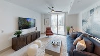 Located in Miami's vibrant Brickell neighborhood, this single-floor residence showcases a contemporary design defined by clean lines, neutral tones, and high-quality finishes throughout. Light-toned porcelain tile flooring runs consistently across the space, contributing to a cohesive and sophisticated aesthetic.

The kitchen is a standout feature, equipped with flat-front cabinetry in warm wood tones, white quartz countertops, a subway tile backsplash, and stainless steel appliances including a French door refrigerator and built-in microwave. A central island with seating provides both functionality and a casual dining option, while pendant lighting adds an elegant touch.

The living area is bright and open, benefiting from floor-to-ceiling sliding glass doors that lead to a private balcony with expansive Miami city skyline views. A ceiling fan and generous natural light enhance the airy atmosphere.

The primary bedroom features direct balcony access through large sliding glass doors, city views, and a calm, neutral palette. The en-suite bathroom offers a long, double-sink vanity with wood cabinetry, backlit mirrors, and a separate shower area. A second bedroom provides a similarly serene environment with soft natural light filtering through sheer curtains.