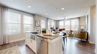 This thoughtfully designed 2-bedroom, 2-bathroom residence offers a seamless single-floor layout that balances comfort and modern style. The open-concept living area is anchored by a chef-inspired kitchen featuring white cabinetry, granite countertops, a large center island with bar seating, stainless steel appliances, and a decorative tile backsplash. The kitchen flows directly into the dining and living areas, which are bathed in natural light from expansive windows with views of the surrounding neighborhood. Light wood-style flooring runs throughout the main living spaces, lending a clean, cohesive aesthetic.

The primary bedroom is a spacious retreat with large windows, a ceiling fan, and plush carpeting. It is complemented by a well-organized walk-in closet featuring multi-level shelving and hanging rods. The secondary bedroom offers similar brightness and comfort. Both bathrooms are finished with granite vanities, white cabinetry, and tile-surround tub-shower combinations.

A dedicated hallway connects the bedrooms and includes a convenient in-unit laundry closet. Throughout the residence, recessed lighting, neutral tones, and quality finishes create a refined yet welcoming ambiance suited for everyday living.