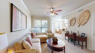 Located at 9000 Almeda Rd in Houston, TX, this single-floor residence offers a thoughtfully designed layout with one bedroom and two full bathrooms. The living room is bright and welcoming, featuring elegant crown molding, a ceiling fan with light fixture, and large windows that invite generous natural light and views of the surrounding greenery. A dedicated dining area flows naturally from the living space, creating an open, cohesive common area. The galley-style kitchen is outfitted with warm wood cabinetry, dark granite-style countertops, tile flooring, and black appliances including a range, microwave, and dishwasher — providing efficient functionality in a compact footprint. The carpeted bedroom is a comfortable retreat with windows on two walls, enhancing natural light, and opens to a generously sized walk-in closet with multi-tier wire shelving. The primary bathroom features dual sinks, warm wood vanity cabinetry, and dark countertops, with an in-unit washer included. A second full bathroom offers a tiled tub/shower combination. The entryway hallway features a built-in niche, adding an architectural detail that enhances the overall refined character of this Houston residence.
