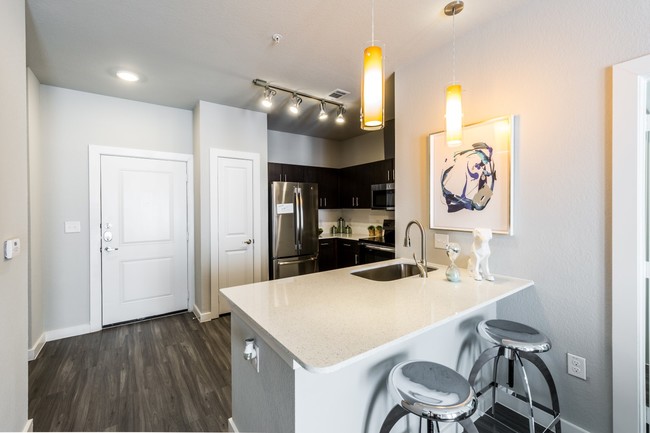 Kitchen island with white quartz countertops, modern lighting fixtures looking into kitchen - Urban North