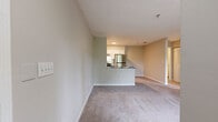 This single-floor unit offers a well-organized layout comprising a living room, kitchen, bedroom, bathroom, and closet. The living room serves as the central gathering space, finished with neutral-toned carpet and bathed in natural light from a large sliding glass door that opens directly onto a private outdoor balcony, providing pleasant outdoor views and seamless indoor-outdoor connectivity. The entry door is also located within this space, contributing to a straightforward, accessible floor plan.

The kitchen is positioned adjacent to the living area and features a peninsula-style counter that visually separates the two spaces while maintaining an open feel. White cabinetry, granite-style countertops, light wood-look flooring, and stainless steel appliances—including a full-size refrigerator and gas range—give the kitchen a clean, functional character.

The bedroom is a comfortably sized private retreat with soft carpeting, neutral walls, and a window that allows natural light and outdoor views. A dedicated closet provides practical storage.

The bathroom includes a white vanity with granite-style countertops, a combined tub and shower with white tile surround, and wood-look tile flooring, resulting in a tidy, cohesive finish throughout.