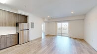 This well-designed 2-bedroom, 2-bathroom unit at 3057 W Pico Blvd in Los Angeles offers a clean, modern aesthetic throughout. Light-toned hardwood flooring runs continuously across the entire space, creating a cohesive and airy feel. The open-concept kitchen and living area serves as the heart of the unit, featuring a fully equipped kitchen with wood-grain cabinetry extending to the ceiling, stainless steel appliances including a gas range, microwave, dishwasher, and refrigerator, along with white quartz countertops. The adjacent living room is generously proportioned, bathed in recessed lighting and offering an open flow toward the hallway and bedrooms. The spacious primary bedroom includes large mirrored sliding closet doors that enhance the sense of light and space, along with a window offering outdoor views. The second bedroom is equally well-sized and bright, featuring its own window with natural light. Both bathrooms are finished in a clean, minimalist style, with one featuring a shower-tub combination and the other providing access to an in-unit stacked washer and dryer. Throughout the unit, crisp white walls and thoughtful structural details contribute to a fresh, contemporary atmosphere.