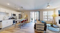 Located on Richmond's iconic Monument Avenue, this well-appointed 2-bedroom, 2-bathroom residence offers a thoughtfully designed single-floor layout that maximizes comfort and functionality. The open-concept kitchen and living area serves as the heart of the home, featuring wide-plank hardwood-style flooring, a kitchen island with seating, white shaker cabinetry, subway tile backsplash, and a full suite of stainless steel appliances. Pendant lighting above the island adds a modern touch, while the seamless flow into the living room — complete with a sleek built-in electric fireplace and large windows — creates a bright, inviting atmosphere. Sliding glass doors lead to a private balcony with outdoor views. The primary bedroom offers plush carpeting, a ceiling fan, generous natural light, and access to a dedicated closet. The second bedroom is equally well-sized with soft carpeting and ample storage. Both bathrooms feature white vanity cabinetry with granite-style countertops and hardwood-style flooring. Additional highlights include a dedicated laundry area and two closets, providing practical everyday convenience throughout this modern Richmond residence.