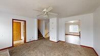 Located at 1421 Jack Pine Way in Kalamazoo, Michigan, this substantial three-story property offers eight bedrooms and five bathrooms, making it well-suited for large households or multi-occupant living. The layout is distributed thoughtfully across three floors, with the ground level serving as a compact entry point, the middle floor offering the largest share of common living space, and the upper floor providing the most expansive footprint of the three.

The main living area features neutral carpet flooring, white walls, and a ceiling fan with light fixture, creating a bright and airy atmosphere. An open sightline connects the living room to the kitchen, which is outfitted with warm oak cabinetry, light countertops, a gas range, dishwasher, and tile flooring. A window in the kitchen brings in natural light and an outdoor view.

The bedrooms are carpeted and finished in clean white tones, each featuring vertical blind-covered windows that allow for adjustable natural light. The primary bedroom offers a comfortable, well-proportioned space. Throughout the home, six-panel wood doors add a classic touch.

The bathrooms include tile flooring and oak vanities. One bathroom features a jetted soaking tub with a tiled shower surround, while others offer standard tub-shower combinations. Four staircases connect the floors, facilitating smooth circulation throughout this generously sized, multi-level home.