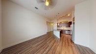 This single-floor residence is designed with a clean, contemporary aesthetic that balances functionality and style. The open-concept living and kitchen area is anchored by warm-toned hardwood-style flooring that flows seamlessly throughout the main space. Elevated ceilings contribute to a generous sense of volume, while a ceiling fan adds practical comfort to the living area.

The kitchen is a standout feature, showcasing rich dark-wood cabinetry, granite countertops, and a decorative tile backsplash in a stacked mosaic pattern. Stainless steel appliances — including a refrigerator with ice and water dispenser, range, microwave, and dishwasher — offer a polished, modern look. Pendant lighting above the kitchen island adds both task illumination and visual appeal. Track lighting further enhances the cooking space.

The bedrooms are finished with plush, neutral-toned carpeting and feature ceiling fans. One bedroom benefits from a large multi-panel window that invites natural light and exterior views. An additional smaller carpeted room provides flexible use as a bedroom, office, or storage space.

The bathroom includes a dark-wood vanity with a granite countertop, an undermount sink, and light tile flooring. A stacked washer and dryer unit is conveniently located nearby, streamlining daily routines.