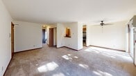 Located at 7626 Radcliffe Drive in Madison, Wisconsin, this 2-bedroom, 1-bathroom unit offers a well-organized single-floor layout designed for comfortable everyday living. The open living area is finished with neutral carpet and light-toned walls, allowing natural light to filter in through large windows. A ceiling fan adds to the functionality of the main living space, which connects seamlessly to a pass-through kitchen. The kitchen features warm wood cabinetry, granite-look countertops, tile flooring, and black appliances, including a refrigerator. A door directly off the kitchen leads to the dedicated in-unit laundry room, which houses a full-size washer and dryer with overhead wire shelving. Both bedrooms are carpeted and finished with warm wood trim, offering a quiet and comfortable atmosphere. The primary bedroom includes a closet and connects to additional interior spaces, while the second bedroom benefits from a window with natural light and baseboard heating. The shared bathroom is clean and functional, featuring a vanity with dark countertops, white cabinetry, tile flooring, and a tub-shower combination with a curtain rod.