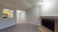 This single-floor residence offers a thoughtfully designed layout with a seamless flow between living, dining, and kitchen areas. The living room serves as the centerpiece of the home, highlighted by a tile-surround fireplace with a clean white mantel and direct access to a private balcony through sliding glass doors, allowing natural light to fill the space. Plush, neutral-toned carpet extends throughout the main living areas and bedrooms, contributing to a warm and comfortable atmosphere.

A pass-through window connects the living and dining area to the kitchen, enhancing the open feel of the space. The kitchen features light wood cabinetry, light-toned countertops, wood-look vinyl flooring, and stainless steel appliances including a refrigerator, dishwasher, and range with microwave.

The bedroom is generously sized, offering mirrored sliding closet doors with built-in shelving for ample storage. A second carpeted room with a window and baseboard heater provides additional flexible living space. The bathroom includes a full tub-shower combination, wood-look flooring, and a linen storage area. The unit also accommodates an in-unit washer, adding everyday convenience.
