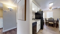 This single-story residence offers a thoughtfully organized layout across two bedrooms and two bathrooms. The living room serves as the heart of the home, featuring wood-style plank flooring, a textured ceiling, and a ceiling fan with integrated lighting. Neutral wall tones create a calm, versatile backdrop throughout the space.

The galley-style kitchen is efficiently designed with white cabinetry, light countertops, and black appliances including a refrigerator, electric range, dishwasher, and microwave. It opens directly into the dining area, which benefits from natural light through a large window and is anchored by a ceiling fan overhead—an ideal setup for everyday dining and entertaining.

The primary bedroom offers carpet flooring, a wide sliding-door closet, and a bright window with blinds. The second bedroom is similarly appointed with carpeted floors and natural light. Each bathroom has a distinct character: one features a tub-shower combination, while the other includes a standalone shower stall. Both display wood-style flooring and clean, functional fixtures with brushed nickel hardware. A connecting hallway ties the layout together efficiently.