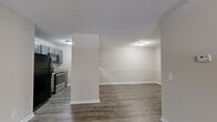 Located in Acworth, GA, this single-floor, 2-bedroom, 1-bathroom unit offers a practical and comfortable layout with a clean, neutral aesthetic throughout. The open-concept living, dining, and kitchen area forms the heart of the home, featuring durable grey wood-look flooring and a textured ceiling. The living room is bright and airy, benefiting from a ceiling fan and access to a private balcony through a sliding door, with a large window that draws in natural light. The kitchen is efficiently designed with grey cabinetry, light granite-style countertops, black appliances including a refrigerator, range, and over-the-range microwave, and wood-look flooring that continues from the main living space. The entryway features tile flooring that transitions seamlessly into the main living area. Both bedrooms are carpeted, offering a softer feel underfoot. The spacious primary bedroom includes an arched architectural accent leading to a windowed alcove, adding a distinctive design touch. The full bathroom is well-appointed with grey cabinetry, a wide granite-style vanity countertop, and a large mirror. A hallway connects the private areas of the home, and four closets provide ample storage. Additional conveniences include a dedicated laundry area and utility room.