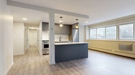 Located in the heart of Ottawa's Centretown neighbourhood, this thoughtfully updated 2-bedroom, 1-bathroom unit at 257 Lisgar Street offers a well-designed open-concept layout. Light wood-style flooring runs throughout the entire space, creating a cohesive and contemporary feel.

The combined living, dining, and kitchen area forms the centrepiece of the unit. The modern kitchen is equipped with stainless steel appliances — including a full-size refrigerator, electric range, and dishwasher — complemented by sleek grey cabinetry, white countertops, and a black undermount sink. A central island with pendant lighting serves as both a prep area and a casual dining spot, while large windows along the exterior wall invite generous natural light and urban views of the surrounding cityscape.

Both bedrooms are comfortably sized, with the primary bedroom offering a built-in closet with panel doors. The unit also features an impressive five closets in total, providing abundant storage throughout. The full bathroom includes a soaker tub with tiled surround, a vanity with storage, and matte black fixtures that add a modern accent.

The clean, neutral palette of warm whites and soft greys throughout the space creates a bright, move-in-ready environment well suited to urban living.