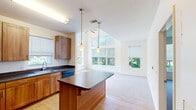 Located at 8 Norden Pl in Norwalk, CT, this two-floor residence offers three bedrooms, two bathrooms, and a thoughtfully designed layout. The open-concept kitchen and living area is an immediate highlight, featuring warm wood cabinetry, dark countertops, a central island with pendant lighting, and hardwood flooring. The adjacent living room benefits from dramatic vaulted ceilings lined with expansive multi-pane windows and a ceiling fan, flooding the space with natural light and lush tree-lined views. The generously sized primary bedroom continues the vaulted ceiling design, boasting a wall of oversized windows with transom panels above, a ceiling fan, and plush carpeting. It includes a dedicated walk-in closet with built-in shelving for ample storage. The additional bedrooms are bright and well-proportioned, each with carpet flooring and windows overlooking the surrounding greenery. Both bathrooms are clean and functional, featuring wood vanities, white countertops, tiled tub-shower combinations, and well-lit mirrors. Throughout the residence, neutral tones and natural light create a calm, welcoming ambiance suited for comfortable everyday living.