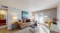 This single-floor residence offers a thoughtfully designed layout that balances comfort and functionality throughout its key living areas. The living room serves as the heart of the home, bathed in natural light streaming through a set of classic French doors that lead to the outdoors. Soft carpeting, neutral gray walls, and generous wall space make it an inviting and versatile area for relaxing or entertaining. The galley-style kitchen features warm oak cabinetry lining both sides, white appliances including a refrigerator and range, light countertops, and hardwood flooring that adds a touch of warmth. A louvered door provides access to a dedicated laundry area, adding everyday convenience. The primary bedroom is a serene retreat, carpeted and well-lit by a large window with outdoor views, providing a calm and restful atmosphere. A second bedroom mirrors this comfort with its own soft carpeting and ample natural light. The bathroom continues the warm aesthetic with rich wood vanity cabinetry, a broad mirror, and hardwood flooring in the entry corridor. Throughout the residence, the consistent use of neutral tones, natural materials, and well-placed windows creates a cohesive, comfortable living environment.