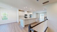This well-appointed two-story home in Ellicott City, Maryland offers a thoughtfully designed layout spread across two floors. The main level features an open-concept kitchen and living room, where light hardwood-style flooring, recessed lighting, and large windows create a bright and welcoming atmosphere. The kitchen is a standout, boasting crisp white shaker cabinetry, granite countertops, a central island with sink, and stainless steel appliances including a French door refrigerator, electric range, and built-in microwave. The open flow into the living area makes this level ideal for both everyday living and entertaining. Upstairs, three bedrooms provide comfortable accommodations, with the generously sized primary bedroom offering ample space and a walk-in closet with wire shelving. The additional bedrooms feature plush carpeting and large windows with natural tree and neighborhood views. The full bathroom includes a glass-enclosed tile shower with a built-in bench and a white vanity. A dedicated laundry room on the upper level is equipped with a stacked washer and dryer unit and granite-topped cabinetry. With three closets, a hallway, and two staircases, this home balances functional design with modern comfort.