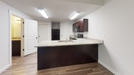 This two-story home is designed with a clean, contemporary aesthetic and a practical layout across both levels. The main floor features an open living area bathed in natural light through window blinds, with durable wood-look flooring that extends throughout. A staircase connects the two levels, reinforcing the home's spacious vertical flow.

The kitchen is a standout feature, centered around a large peninsula with a granite countertop and double sink, ideal for both meal preparation and casual dining. Rich dark espresso cabinetry lines the walls, complemented by matching granite surfaces, black appliances including a range, over-the-range microwave, and refrigerator, all set on light hardwood-style flooring.

The upper level hosts multiple carpeted bedrooms, each offering soft natural light through window blinds and generous proportions. One bedroom provides direct access to a hallway landing area, adding to the functional flow of the upper floor.

The bathrooms are consistently finished with granite-topped dark vanities, undermount sinks, and full tub-shower combos set against clean white surrounds, with tile flooring completing each space. Throughout the home, neutral tones, clean lines, and consistent finishes create a cohesive and move-in-ready environment.