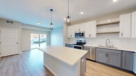 Located at 13972 Edgewood Ave in Savage, MN, this thoughtfully designed one-bedroom, one-bathroom residence offers a contemporary living experience across a single floor. The open-concept layout maximizes the use of space, seamlessly connecting the kitchen and living area to create an inviting, functional environment.

The kitchen is a standout feature, showcasing a two-tone cabinet design with crisp white upper cabinets and soft gray-blue lower cabinets, complemented by a white quartz countertop and a classic subway tile backsplash. A central island with a matching white countertop provides additional prep and dining space, while stylish industrial pendant lights hang above. A full suite of stainless steel appliances — including a refrigerator, range, microwave, and dishwasher — complete the space. Light wood-look flooring and a sliding glass door to the exterior fill the living area with natural light.

The bedroom offers a comfortable, carpeted retreat with a window overlooking the surroundings, and direct access to a dedicated walk-in closet outfitted with wire shelving and hanging rods for generous storage. The bathroom features a white vanity with a clean white countertop, a bold black-framed mirror, and matching matte black hardware accents throughout.