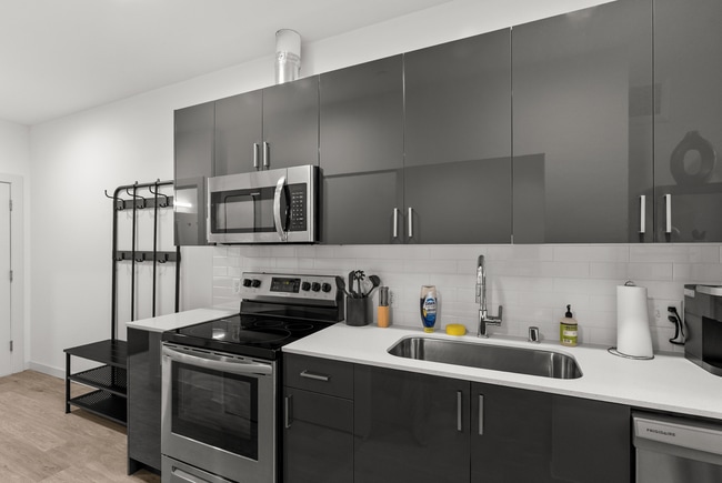 Modern kitchen featuring stainless steel appliances, contemporary cabinetry, and clean, bright finishes. - The Ruby Apartments