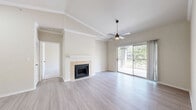 Located at 7101 Chase Oaks Boulevard in Plano, TX, this 2-bedroom, 2-bathroom residence offers a well-designed single-level layout with a bright, neutral palette throughout. The open living room serves as the heart of the home, featuring a tile-surround fireplace, a tray ceiling with a ceiling fan, and light wood-style flooring that extends across the main living areas. Sliding glass doors lead to a private covered balcony overlooking mature trees, bringing natural light and serene outdoor views into the space.

The kitchen is positioned adjacent to the living area and features a wraparound peninsula with a white countertop, white cabinetry, and black appliances, including a refrigerator, microwave, and gas range. A hallway with vaulted ceilings connects the main living space to the bedrooms, with built-in cabinetry adding functional storage along the way.

The primary bedroom is generously sized with soaring vaulted ceilings, plush carpet flooring, a ceiling fan, and direct access to a private en-suite bathroom. The en-suite features a white vanity with a undermount sink, dark hardware accents, a large framed mirror, and a tub-shower combo. The second bedroom also features carpet flooring and a double-door closet. A second full bathroom with a clean, modern vanity serves the remaining rooms. The hallway and closet complete this efficiently arranged and move-in ready home.