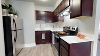 Located at 41 Winterhaven Dr in Newark, Delaware, this single-floor residence offers a thoughtfully designed living space with a clean, contemporary aesthetic. The kitchen is a standout feature, showcasing rich dark-stained cabinetry that provides generous storage, complemented by crisp white countertops that create a striking contrast. Stainless steel appliances, including an electric range and refrigerator, add a modern touch and are well-integrated into the layout. A single-basin sink is positioned beneath upper cabinetry, maximizing workspace efficiency. The light wood-style flooring runs throughout, lending warmth and continuity to the interior. Neutral light gray walls keep the atmosphere bright and versatile, allowing for a variety of décor styles. An under-cabinet range hood adds both functionality and a refined finish to the cooking area. The overall design balances practicality with modern style, making this a comfortable and functional home in the Newark, Delaware community.