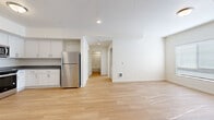 Located at 320 Lincoln St in Fairview, Oregon, this 2-bedroom, 1-bathroom unit offers a thoughtfully designed, single-floor layout with a bright, contemporary aesthetic throughout. Light wood-style flooring flows seamlessly across every room, creating a cohesive and airy feel.

The open-concept living and kitchen area forms the heart of the home. The kitchen is well-appointed with white shaker cabinetry, dark countertops, and a full suite of stainless steel appliances including a refrigerator, range, microwave, and dishwasher. Open shelving adds a practical, modern touch alongside ample upper and lower cabinet storage.

Both bedrooms are comfortably sized, featuring neutral walls, natural light from windows fitted with blinds, and light flooring that continues from the main living area. The primary bedroom offers generous proportions, while the second bedroom is well-suited for a guest room or home office. Each room provides a clean, versatile canvas.

A hallway connects the bedrooms to the full bathroom, which includes a vanity with dark countertops, white cabinetry, wood-look flooring, and a soaking tub with a shower curtain rod. The overall design of the unit is clean and modern, with recessed lighting and a neutral color palette that enhances the sense of openness throughout.