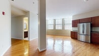 Located at 25 Bittner St in Rochester, NY, this single-floor residence offers three bedrooms and two bathrooms within a well-appointed, open-concept layout. The heart of the home is a generous living and dining area that flows seamlessly into the kitchen, all unified by gleaming hardwood floors that reflect abundant natural light streaming through large windows dressed with vertical blinds. Structural columns add an urban, loft-like character to the open living space.

The kitchen is equipped with rich, dark-wood cabinetry, granite-style countertops, and a full suite of stainless steel appliances, including a refrigerator, range, dishwasher, and built-in microwave. A hallway connects the main living area to the private quarters, where the bedrooms feature plush wall-to-wall carpeting and large windows offering city views. The spacious primary bedroom provides a comfortable retreat, while the two additional bedrooms offer versatility for guests or a home office.

The two bathrooms are finished with clean ceramic tile flooring and tile-surround showers, complemented by dark-wood vanities. A dedicated closet houses a stacked in-unit washer and dryer, adding everyday convenience. The overall design is clean, modern, and functional — ideal for urban living in Rochester.