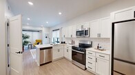 This single-story, one-bedroom, one-bathroom unit offers a thoughtfully organized layout that maximizes its compact footprint. The kitchen serves as a standout feature, showcasing white shaker-style cabinetry with matte black hardware, a classic white subway tile backsplash, and light-toned quartz countertops. Stainless steel appliances — including a gas range, over-the-range microwave, and dishwasher — provide full functionality. The kitchen flows naturally into the living area, which benefits from natural light through roller-shade windows, creating a cohesive and open living space. Light wood-tone flooring runs consistently throughout, lending warmth and visual continuity.

The bedroom is a generously proportioned space for the overall unit size, featuring a window with curtain rod, neutral wall tones, and direct access to a dedicated walk-in closet with built-in shelving. The full bathroom is clean and functional, finished with light flooring, a white vanity with quartz countertop, and a shower/tub combination. Shaker-style interior doors with matte black hardware maintain design consistency throughout the unit, contributing to its modern, cohesive aesthetic.