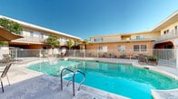 This two-story apartment complex in Los Angeles showcases a Mediterranean-inspired architecture with stucco exterior walls in warm, earthy tones. The property features a central courtyard dominated by a large, rectangular swimming pool, which is securely fenced for safety. Balconies with decorative railings adorn the second floor, providing private outdoor spaces for upper-level units.

The landscaping is a standout feature, with mature trees, including citrus varieties, providing shade and greenery throughout the complex. Well-maintained garden beds line the walkways, filled with a variety of plants, shrubs, and colorful flowers, creating an inviting and serene atmosphere.

Concrete pathways meander through the property, connecting various areas and providing easy access to all units. The complex appears to offer both ground-level and upper-level apartments, with large windows and sliding glass doors that likely allow ample natural light into the living spaces.

Communal areas around the pool include lounge chairs and tables, suggesting a space for residents to relax and socialize. The overall design emphasizes outdoor living and a community feel, typical of Southern California apartment complexes, while maintaining a sense of privacy for residents.