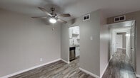 Located at 8411 Deansgate Ln in Dallas, Texas, this single-floor unit offers a clean, contemporary design throughout. The layout, visible in the 3D overview, includes a spacious living area, a dedicated kitchen, bedroom spaces, and a bathroom, all connected in a practical and efficient floor plan.

The living area is open and airy, featuring wood-look flooring in rich, varied tones that runs consistently throughout the unit. Neutral greige-toned walls provide a versatile backdrop, while ceiling fans with integrated lighting serve both the main living space and additional rooms. A large window with vertical blinds allows natural light to fill the space, enhancing its welcoming atmosphere.

The kitchen is designed for functionality, featuring a galley-style layout with white shaker cabinetry, granite-look countertops, a subway tile backsplash, and a double-basin stainless steel sink. Stainless steel appliances—including a refrigerator, electric range, microwave, and dishwasher—complete the space.

The bathroom is finished with full-height grey tile surrounding a soaking tub and shower combination, complemented by granite-look countertops and wood-look flooring. The bedrooms are generously proportioned, offering clean walls and consistent flooring, providing a calm and neutral setting.