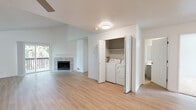 Located in Beaverton, Oregon, this single-floor residence at 14305 SW Sexton Mountain Dr offers a well-designed layout with a clean, contemporary aesthetic throughout. The open living area is a standout feature, boasting soaring vaulted ceilings, a ceiling fan, and light wood-look flooring that creates a bright and airy atmosphere. A tile-surround fireplace serves as the focal point of the living room, complemented by a sliding glass door that opens to a private balcony with views of surrounding greenery, allowing natural light to flow generously into the space. The kitchen is equipped with stainless steel Frigidaire appliances, including an electric range and over-the-range microwave, paired with white cabinetry and light countertops. A dedicated in-unit laundry closet with a full-size washer and dryer adds everyday convenience. The bedroom features plush carpeting and a sliding door with direct access to the balcony, offering a peaceful retreat. The bathroom includes a tub-shower combination with clean white surrounds, wood-look tile flooring, and a vanity with updated gray cabinetry. Throughout the unit, a neutral color palette and textured ceilings contribute to a fresh, move-in-ready feel.