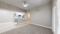This single-floor residence offers four bedrooms and two full bathrooms within a thoughtfully designed layout. The open living area features plush carpet flooring and a ceiling fan overhead, flowing seamlessly into the kitchen via a peninsula bar. The kitchen is outfitted with grey shaker-style cabinetry, marble-look backsplash, white quartz countertops, stainless steel appliances including a range, microwave, refrigerator, and dishwasher, and light wood-look flooring. A skylight adds a bright, airy feel to the galley-style kitchen corridor. Both bathrooms are finished with marble-look tile surrounds in the tub-shower combos, grey vanity cabinetry, white countertops, and light wood-look tile flooring, delivering a clean, contemporary aesthetic. The bedrooms are carpeted and feature neutral grey-toned walls, white blinds, and ceiling fans, with multiple windows allowing natural light to fill the spaces. The primary bedroom provides a comfortable footprint with ample room for furnishings. Two hallways and a dedicated closet contribute to the home's practical flow. Throughout, a cohesive neutral palette and modern hardware create a polished, move-in-ready environment.
