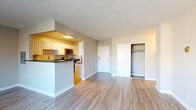 This well-appointed single-floor unit offers a thoughtfully designed open-concept layout finished with light hardwood-style flooring throughout. The spacious living area is bathed in natural light through large windows fitted with blinds, offering views of the surrounding urban landscape. A ceiling fan adds comfort to the living space, which flows seamlessly into the dining area and kitchen via a peninsula-style breakfast bar.

The kitchen is efficiently designed with crisp white cabinetry, dark granite-style countertops, and a full suite of stainless steel appliances, including a gas range, built-in microwave, and dishwasher. Ample upper and lower cabinet storage ensures strong functional utility.

The bedrooms are generously proportioned, each featuring ceiling fans, hardwood-style flooring, and large closets with built-in shelving and hanging rods for organized storage. Natural light fills each room through sizable windows with urban views.

The bathroom features a clean, classic design with white subway tile surrounding a full soaking tub and shower combination. Neutral tones and white fixtures contribute to a fresh, timeless aesthetic throughout.

The unit's overall palette of soft grays and warm whites creates a calm, modern ambiance well-suited for comfortable everyday living.