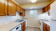 This single-floor unit offers a clean, practical layout designed for comfortable everyday living. Light-toned wood-look flooring runs throughout the space, creating a cohesive and easy-to-maintain foundation across every room.

The open living area is bright and generously sized, with neutral cream-toned walls and natural light filtering in through windows fitted with horizontal blinds. The space flows naturally toward the kitchen and hallway, providing an intuitive sense of connectivity.

The kitchen is equipped with warm honey-toned wood cabinetry — both upper and lower — offering ample storage for cookware and pantry essentials. A single-basin sink, light countertops, a dishwasher, and a white gas range complete the cooking space. A window above the countertop area brings in natural light. Notably, the kitchen also accommodates an in-unit washer, adding significant convenience.

The bedrooms are well-sized with neutral walls and natural light from outdoor-facing windows. One bedroom features a spacious reach-in closet with double doors and a rod for hanging storage.

The bathroom includes a full bathtub with shower surround, a toilet, and a wood-toned vanity with countertop, all finished with the same light wood-look flooring found throughout the unit. White panel doors and clean white trim complete the cohesive interior aesthetic.