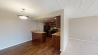 This single-floor residence offers a functional and cohesive layout designed for comfortable everyday living. The kitchen serves as a central highlight, showcasing rich dark wood cabinetry, granite countertops, and a peninsula that provides additional prep space and seating. Black appliances — including a refrigerator, gas range, and over-the-range microwave — are integrated seamlessly throughout. Recessed lighting illuminates the kitchen, which transitions to durable hardwood-style flooring that extends through the main living areas.

The bedrooms are finished with soft, neutral-toned carpet and feature vertical blind-covered windows that invite generous natural light. Each room offers a calm, versatile atmosphere suited for a variety of uses. Closets provide practical built-in storage, and the warm beige wall tones carry a consistent, understated palette throughout.

The bathroom is clean and efficiently designed, featuring a full tub and shower combination with white tile surround and chrome fixtures, complemented by the same hardwood-style flooring found in the main areas.

A standout feature is the in-unit stacked washer and dryer, conveniently located near the bedrooms. The overall design balances practicality with comfort, making this a well-rounded single-floor living space.