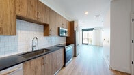 Located at 2490 N Druid Hills Rd in Atlanta, GA, this contemporary two-floor residence offers a thoughtfully designed layout spread evenly across both levels, connected by two staircases. Light wood-toned flooring runs throughout, complementing the clean white walls and modern aesthetic.

The kitchen is a standout feature, outfitted with warm wood cabinetry, dark countertops, a classic white subway tile backsplash, and a full suite of stainless steel appliances including a refrigerator, electric range, built-in microwave, and dishwasher. It flows seamlessly into the adjacent living area, which benefits from large black-framed windows and direct access to a balcony, allowing abundant natural light and outdoor views.

A second living area provides additional flexible space, also featuring expansive black-framed windows that frame views of the surrounding Atlanta neighborhood. Both rooms maintain a bright, airy atmosphere thanks to their light palette and generous glazing.

The two bathrooms echo the same modern design language, featuring wood-grain vanities with white countertops and large framed mirrors. One bathroom includes a frameless glass-enclosed walk-in shower with floor-to-ceiling white tile. A hallway and closet provide practical storage and circulation, rounding out a well-organized and stylish floor plan.