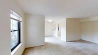 Located at 14 Emily Drive in South Setauket, NY, this single-story home offers a clean, open layout designed for ease of living. The interior is finished with neutral-toned wall-to-wall carpeting that runs throughout the main living areas, contributing to a warm and cohesive aesthetic. Crisp white walls and smooth ceilings maximize the sense of light and openness, creating a bright and airy atmosphere throughout.

The main living area is generously proportioned, flowing naturally into adjacent spaces that provide a versatile floor plan suited to a variety of furniture arrangements and lifestyle needs. A pass-through or counter feature is visible toward the rear of the space, suggesting a connected kitchen area that maintains visual openness while defining distinct functional zones. Natural light enters through well-placed windows, further enhancing the home's welcoming ambiance.

The overall design is understated and move-in ready, with a neutral palette that offers a blank canvas for personalization. The single-floor layout ensures seamless accessibility throughout the home, making it a practical and comfortable option. This property combines functional design with a calm, uncluttered interior in a residential setting in the heart of South Setauket, New York.