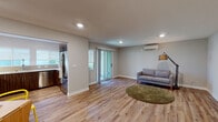 Located at 20010 Rodrigues Ave in Cupertino, CA, this well-designed single-story residence offers a clean, modern aesthetic with thoughtful finishes throughout. The open-concept living area is anchored by warm-toned hardwood-style flooring, recessed lighting, and neutral gray walls that create a bright and welcoming atmosphere. A wall-mounted mini-split HVAC unit ensures year-round comfort, while a sliding glass door connects the living space to the outdoors, filling the room with natural light. The kitchen is a standout feature, showcasing rich dark wood cabinetry, crisp white countertops, a subway tile backsplash, and stainless steel appliances including a dishwasher and refrigerator. Dual windows with roller shades above the sink bring in abundant natural light. A versatile dining or flex area provides additional functional space, complete with recessed lighting and access to interior rooms. The bedroom is a serene retreat, equipped with its own mini-split unit, a bright window, and the same cohesive hardwood-style flooring. The bathroom is clean and functional, featuring wood-look flooring, a window with a roller shade for privacy, and a bathtub with shower. This residence offers a cohesive, move-in-ready living environment in the heart of Silicon Valley.